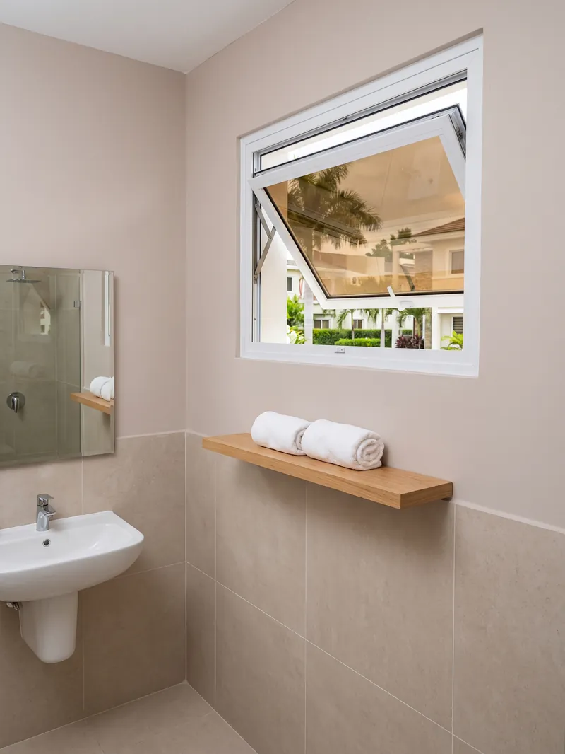 Ventana proyectante de aluminio con vidrio bronce en un baño