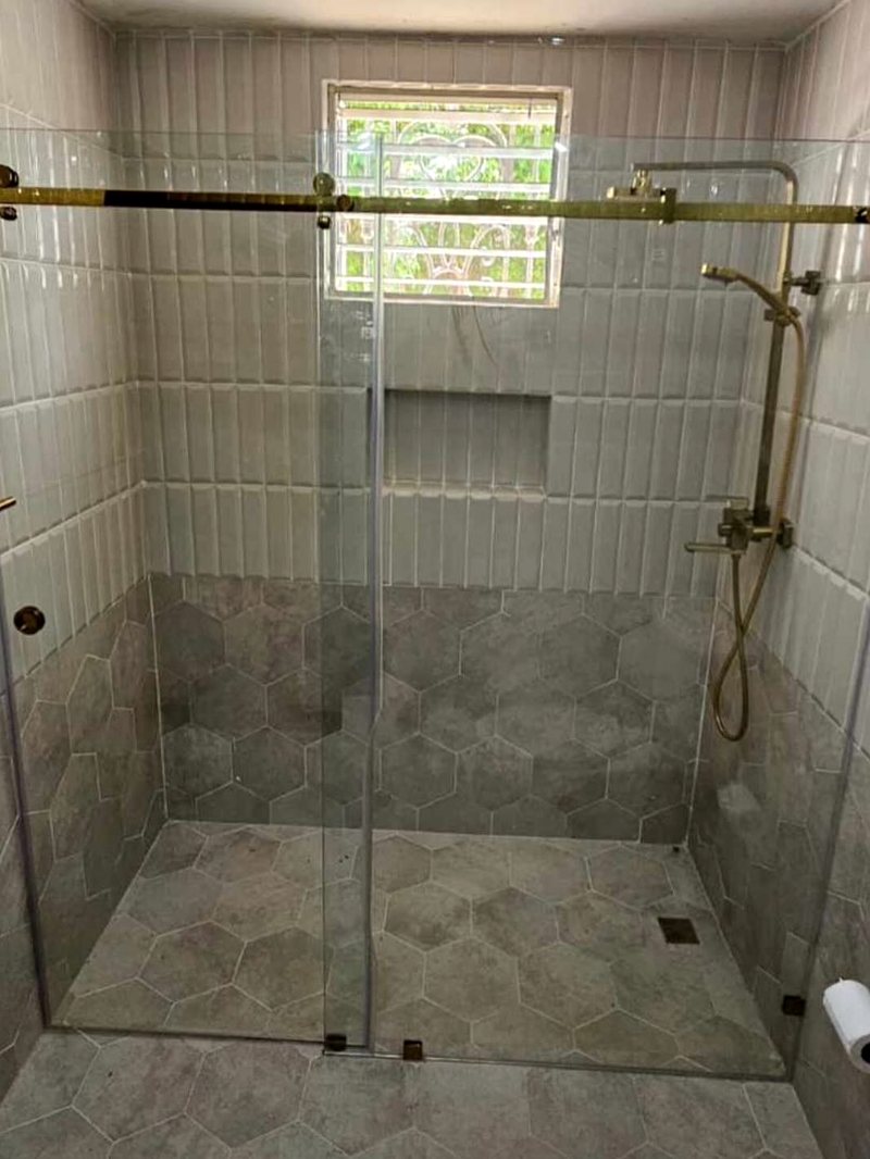 Ducha con puerta corrediza de vidrio templado sobre barra vista
